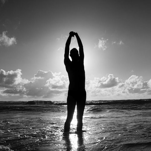 Silhouette of a man stretching against a sunrise, symbolizing energy and peace.